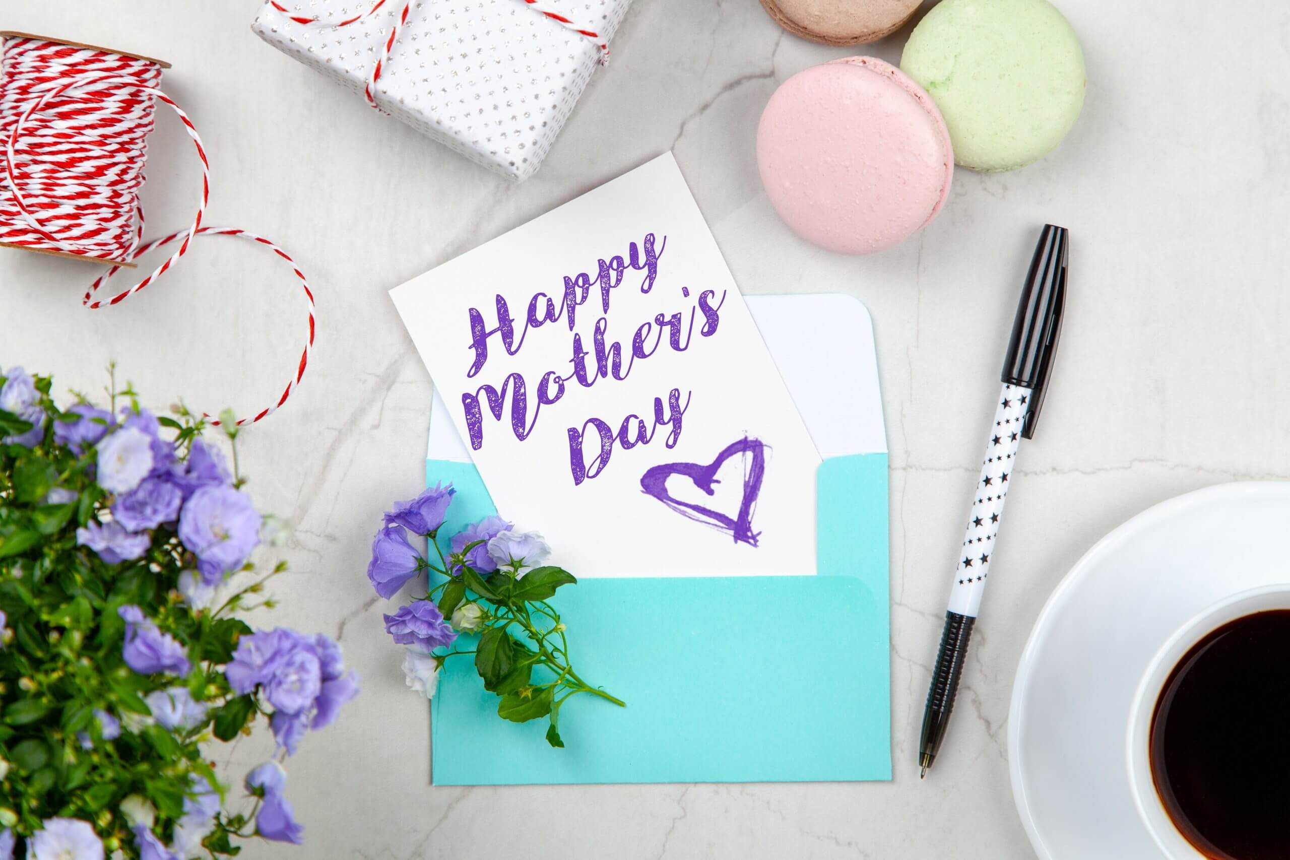 Canva - Happy Mothers Day Card Beside Pen, Macaroons, Flowers, and Box Near Coffee Cup With Saucer