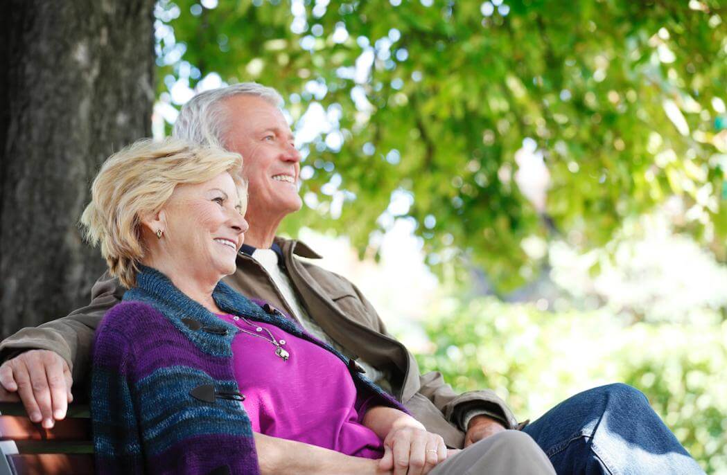 Retired couple sitting outdoors on a bench