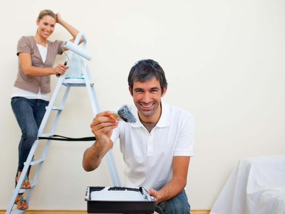 Smiling couple painting a wall of their new house.jpeg